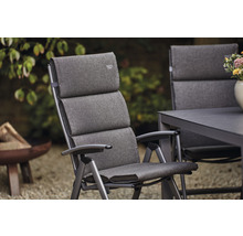 Gepolsterter Gartenstuhl aus Metall mit Armlehnen vor Gartenhintergrund