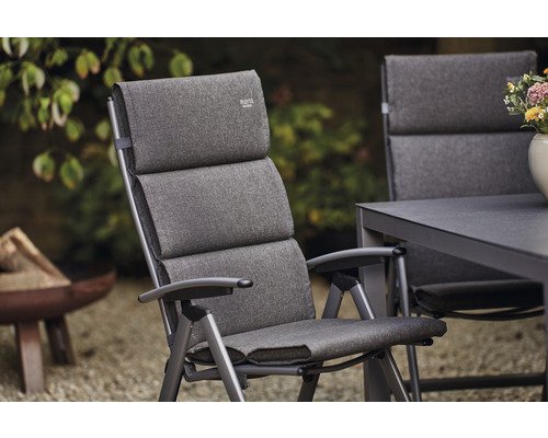 Gepolsterter Gartenstuhl aus Metall mit Armlehnen vor Gartenhintergrund