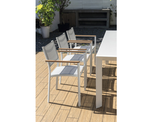 Drei weiße Gartenstühle mit Armlehnen aus Holz und ein weißer Gartentisch auf einer Terrasse.