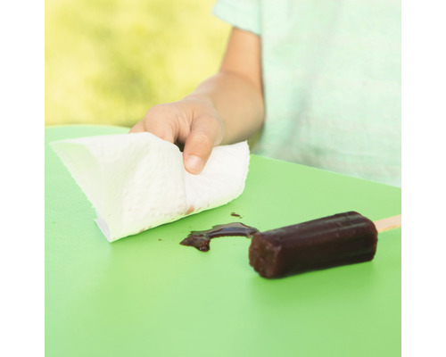 Kind wischt geschmolzenes Eis mit einem Papiertuch von einem Tisch