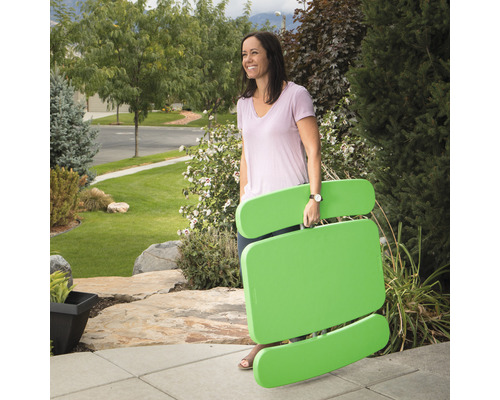 Frau trägt einen zusammengeklappten Picknicktisch im Freien.