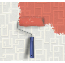 Farbeimer und Farbroller vor einer Wand mit geometrischem Muster