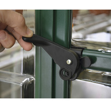 Hand betätigt einen schwarzen Fenstergriff an einem grünen Fensterrahmen