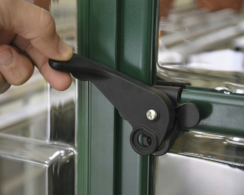 Hand betätigt einen schwarzen Fenstergriff an einem grünen Fensterrahmen