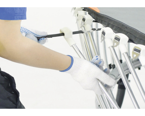 Eine Person mit Handschuhen montiert einen Wäscheständer.