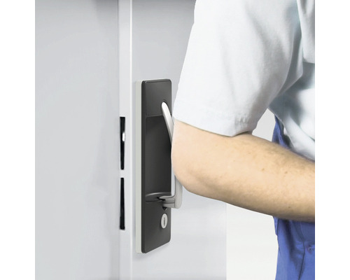 Eine Person öffnet eine Tür mit einem Türschloss und einem Türgriff.