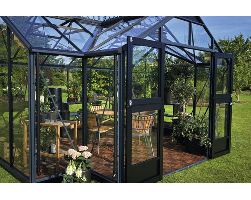 Gewächshaus mit Möbeln und Pflanzen auf einer Rasenfläche