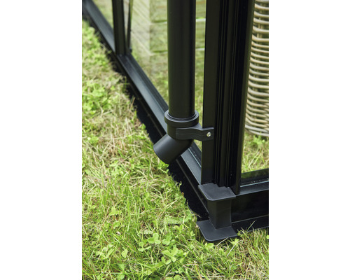 Detailaufnahme eines schwarzen Gewächshausrahmens mit Regenfallrohr und Grasbewuchs