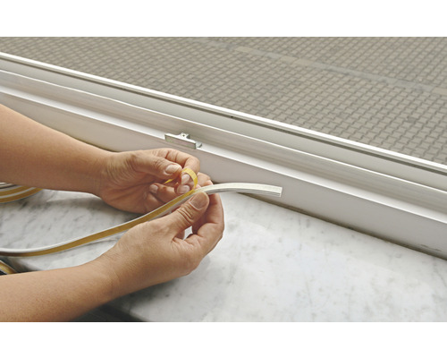 Person entfernt Schutzfolie von Dichtungsband zur Fensterabdichtung