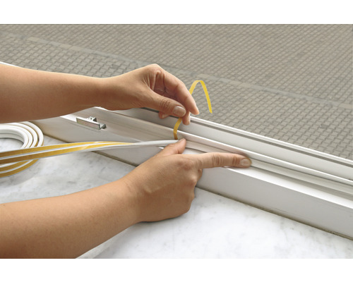 Anbringen eines Dichtungsbandes an einem Fensterrahmen zur Isolierung.