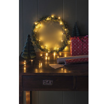 Dekorierte Weihnachtsszene mit Kranz, Lichtern, Geschenk und Tisch