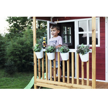 Spielhaus mit Junge, Blumenkästen und Spielzeug auf der Veranda im Garten