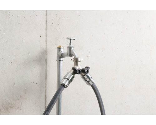 Wasserhahn mit zwei Anschlüssen und Schlauchanschlüssen vor einer Betonwand