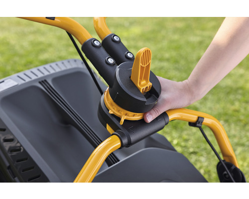 Detailansicht eines Rasenmähers mit Hand am Griff zur Höhenverstellung.