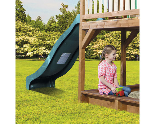 Spielturm mit Rutsche und spielendem Kind im Sandkasten