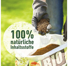 Eine Hand mit Gartenhandschuh hält Dünger über eine Tüte mit der Aufschrift Bio und dem Hinweis 100 Prozent natürliche Inhaltsstoffe.