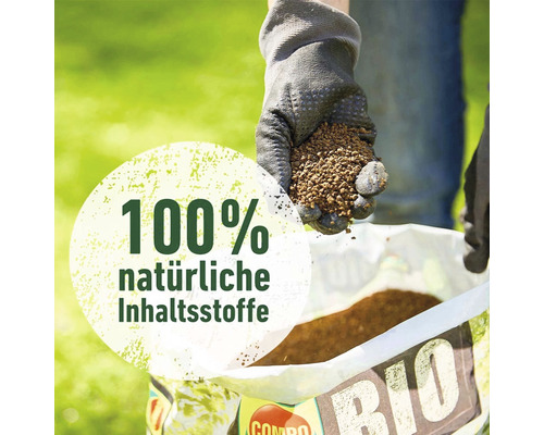 Eine Hand mit Gartenhandschuh hält Dünger über eine Packung organischen Dünger