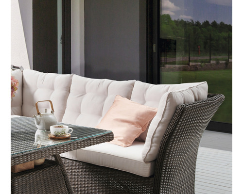 Terrasse mit Sitzgruppe aus Rattan, bestehend aus Sofa, Tisch und Kissen