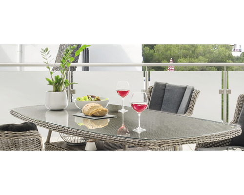 Gedeckter Gartentisch mit Gläsern, Salatschüssel und Brot auf einem Balkon