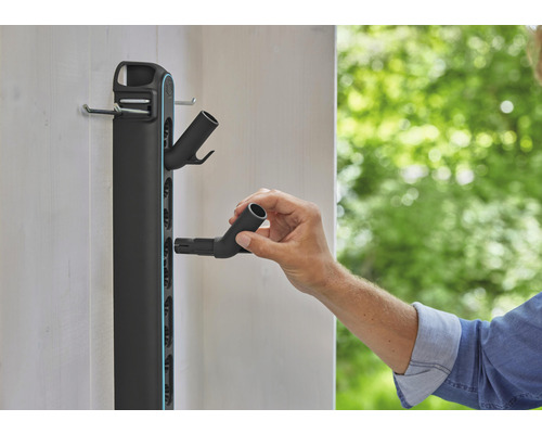 Gartengerätehalter zur Wandmontage mit Person, die einen Schlauchanschluss anbringt