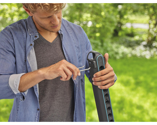 Mann montiert einen Gartenschlauchwagen mit einem Montagewerkzeug im Garten.
