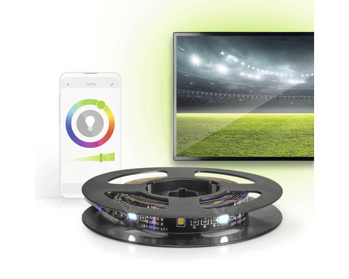 LED-Streifen auf einer Spule, Smartphone und Fernseher im Hintergrund