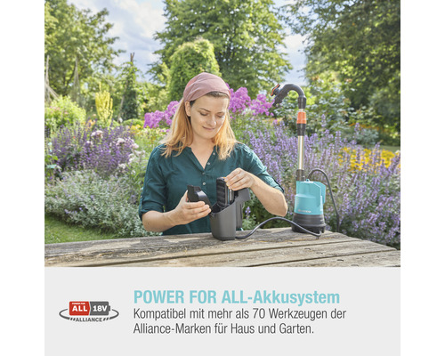 Eine Frau setzt einen Akku in eine Gardena Schmutzwasserpumpe auf einem Holztisch im Garten ein.