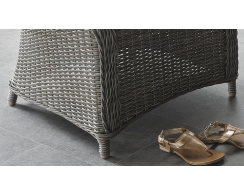 Detailansicht eines Rattanmöbels mit Füßen und einem Paar Sandalen