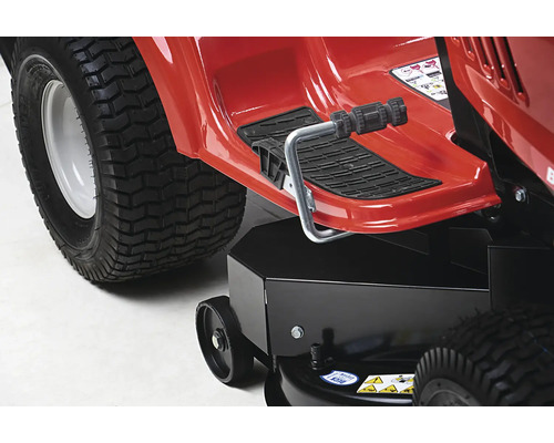 Detailansicht eines roten Aufsitzmähers mit Fußstütze und großem Reifen