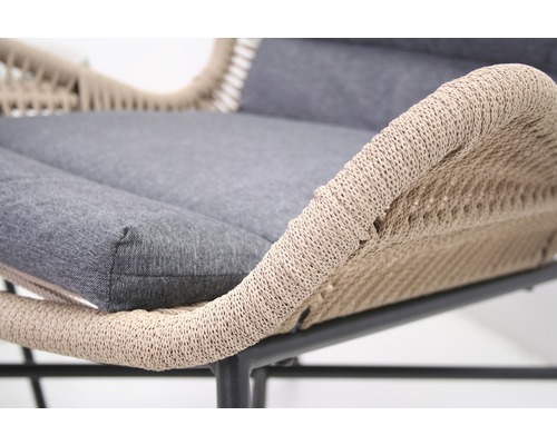Detailansicht eines Gartensessels mit geflochtener Sitzfläche und grauen Polstern.