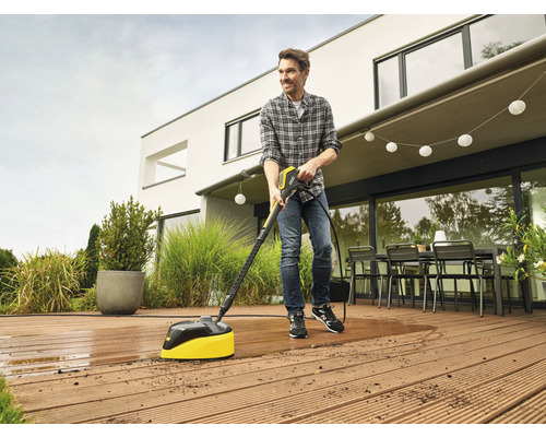 Ein Mann reinigt eine Holzterrasse mit einem Terrassenreiniger.
