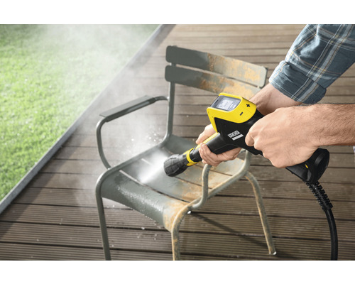 Eine Person reinigt mit einem Kärcher Hochdruckreiniger einen Gartenstuhl.