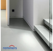 Heller Raum mit Betonboden und Treppe mit Glasgeländer. Remmers Logo.