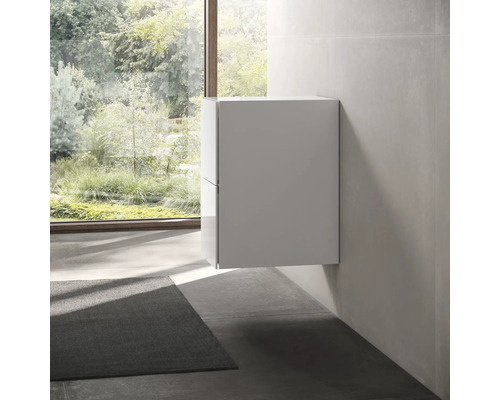 Wandhängender Badezimmerschrank in einem hellen Raum mit Fenster und Teppich