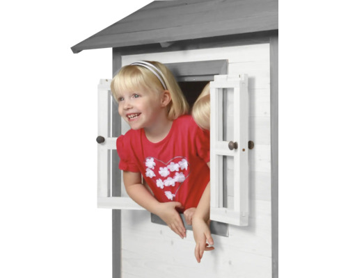 Mädchen schaut aus dem Fenster eines Spielhauses aus Holz