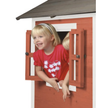 Mädchen schaut aus dem Fenster eines Spielhauses aus Holz