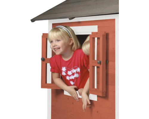 Mädchen schaut aus dem Fenster eines Spielhauses aus Holz