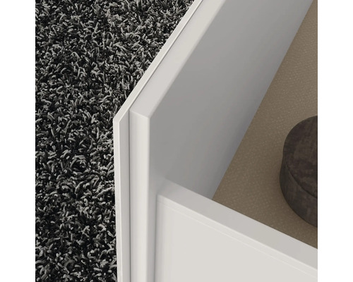 Detailansicht einer offenen, weißen Schublade vor einem Teppich