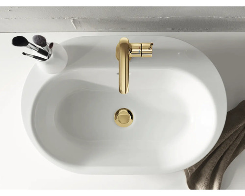 Aufsicht auf ein weißes Waschbecken mit goldenem Wasserhahn und einem Behälter mit Make-up Pinseln