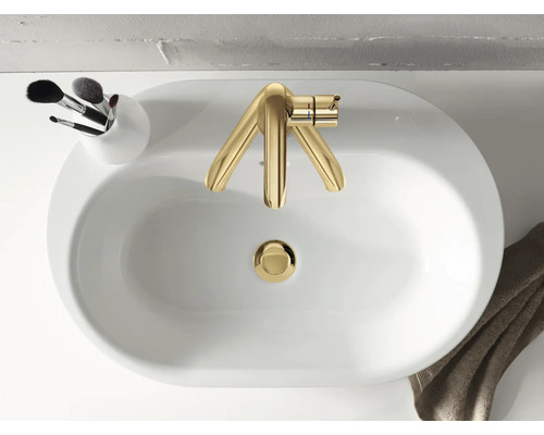 Aufnahme von oben eines Waschbeckens mit goldener Armatur, einem Halter mit Make-up-Pinsel und einem Handtuch