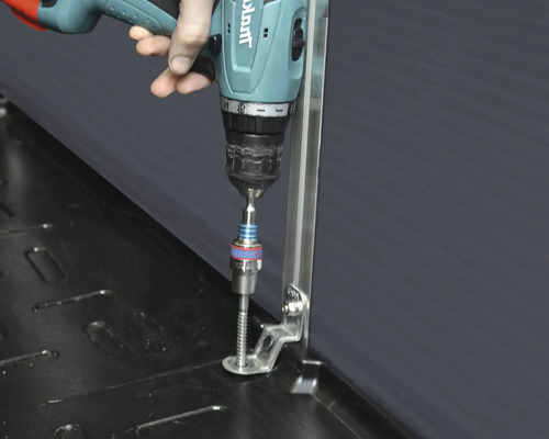 Eine Person befestigt mit einem Akkuschrauber eine Schraube an einer Metallhalterung.