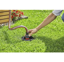 Eine Person schliesst einen Gartenschlauch an einen Wasseranschluss im Garten an