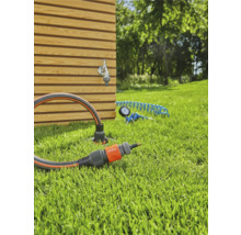 Gartenszene mit Wasserhahn, Gartenschlauch und Anschlussstück auf Rasen