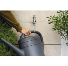Person füllt eine Gießkanne mit Wasser aus einem Wasserhahn im Garten