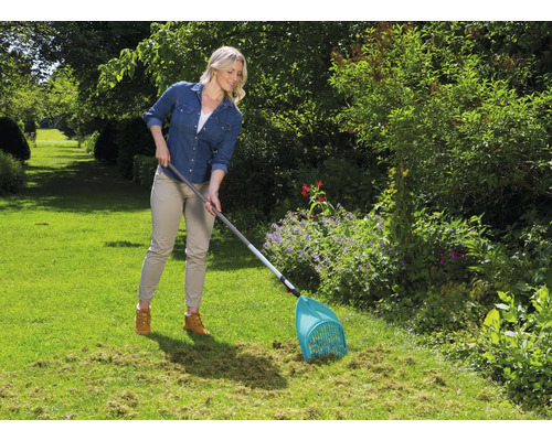 Frau arbeitet mit einem Laubsammler im Garten.