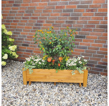 Blumenkasten aus Holz mit verschiedenen Blumen bepflanzt vor einer Ziegelwand