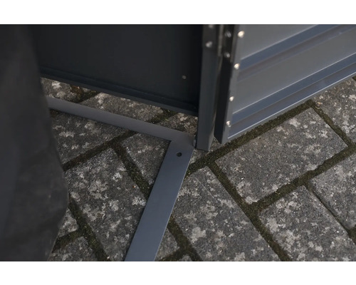 Detailansicht eines Metallgerätehauses mit Bodenrahmen auf Pflastersteinen