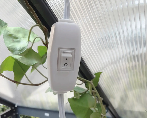 Ein weißer Schalter an einem Kabel, montiert in einem Gewächshaus.