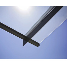 Detailaufnahme eines Glasvordachs mit Metallrahmen vor blauem Himmel