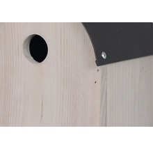 Detailansicht eines Nistkastens aus Holz mit Metalleindeckung und rundem Eingangsloch.
